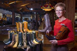 Connie Smith, a ladies department manager, displays boots at the Pinto Ranch western wear store in the Fashion Show Mall Monday, November 19, 2012. Smith is holding a Old Gringo Eagle Crystal ladies boot, left, and  Lucchese Classic mens boot with a crocodile belly foot and a hand-tooled shaft.