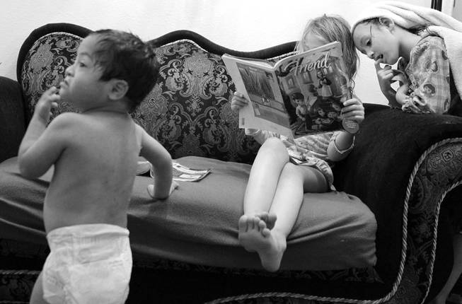 Henry, 3, watches television as Almalinda, 7, and Maria, 5, read a book at home in Las Vegas on Wednesday, November 28, 2012.