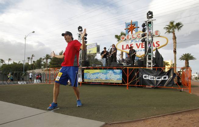 A runner stops to have his photo taken in front of the Welcome To Las Vegas sign during the Zappos.com Rock 'n' Roll Las Vegas Marathon Sunday, Dec. 2, 2012. The band Drive performs behind him.