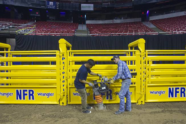 Adrian Torres, left, and Josh Jordan use an impact rammer to compact dirt around the bull chutes as they prepare the Thomas & Mack Center for the National Finals Rodeo Sunday, Dec. 2, 2012. This year's NFR begins Thursday, Dec. 6 and runs through Saturday Dec. 15.