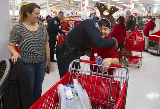 North Las Vegas Police officer Marcus Cook gives a hug to Leonardo Solis as his mother Eida Gonzalez looks on during an annual Shop With A Cop event at the Target store at 2189 W. Craig Rd. in North Las Vegas, Wednesday, December 5, 2012.
