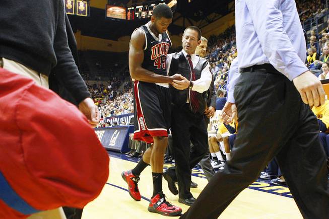 UNLV trainer Dave Tomchek leads forward Mike Moser off the floor after a Cal player fell on his arm during the first half of their game Sunday, Dec. 9, 2012 at Haas Pavilion in Berkeley, Calif.