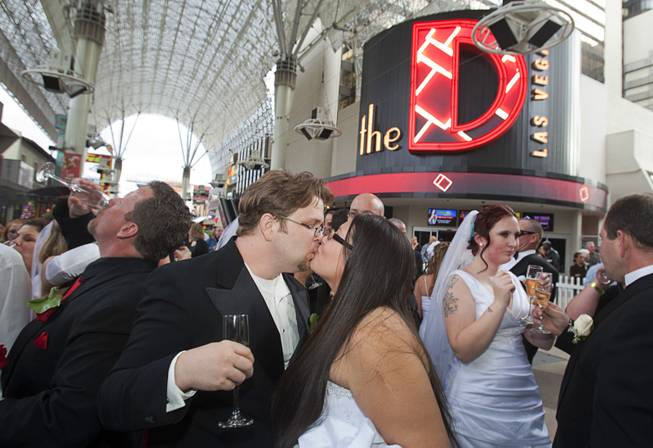 Couples celebrate with champagne at the Fremont Street Experience in downtown Las Vegas Wednesday, Dec. 12, 2012. Ryan Maluka and his bride Danielle Martinez kiss at center. Twelve couples got married at 12:12 pm at the Chapel of the Flowers as part of a KOMP 92.3 radio station promotion. The D Las Vegas put the couples up in newly upgraded rooms, hosted a reception and gave them tickets to "Marriage Can Be Murder," a comedy, murder-mystery dinner show.