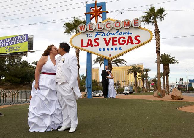 Jacqueline Plysier and Dominique Vilay of Paris, France, kiss as they pose for photos after getting married in Las Vegas on Wednesday, Dec. 12, 2012. Eric Howell and Paola Teran of Stanton, Calif., are in the background. Las Vegas wedding chapels were busy all day as many couples wanted to get married on the unique date of 12-12-12.