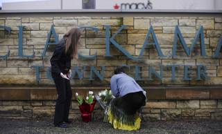 Leslie King, right and Tenille Beseda place flowers Wednesday Dec. 12, 2012, at the entrance to the scene of a multiple shooting yesterday at Clackamas Town Center Mall in Clackamas, Ore.  A gunman who opened fire on shoppers at a Portland mall had no connection to the two people he fatally shot and wanted to kill as many people as possible, police said Wednesday. 