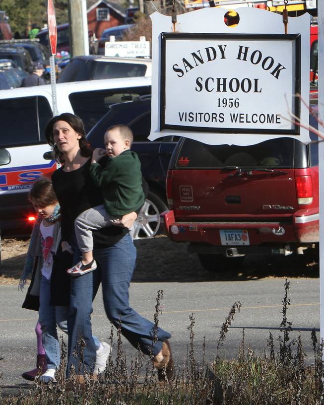 A parent walks away from the Sandy Hook Elementary School with her children following a shooting at the school in Newtown, Conn. on Friday, Dec. 14, 2012.  