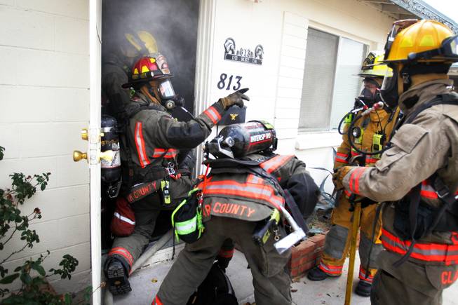 Members of Clark County Fire Department Engine 27 run a search and rescue drill at a home filled with theatrical smoke near McCarran Airport in Las Vegas on Monday, December 17, 2012.