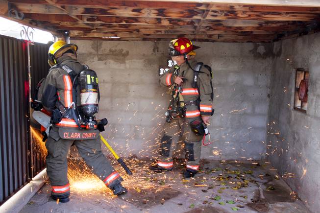 Firefighter Chris Stolworthy, left, opens a gate while Captain Ray McCorvey looks on during a Clark County Fire Department search and rescue drill at a home filled with theatrical smoke near McCarran Airport in Las Vegas on Monday, December 17, 2012.