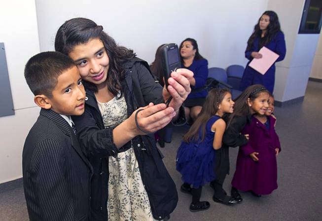 David, 9, and Vanessa Maciel, 12, take a photo as they wait outside a courtroom at family court Thursday, Dec. 20, 2012. The family officially adopted four more children for a total of eleven children.