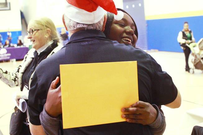Endia Spann hugs United Way's Ira Koplow after picking up a gift card worth $500, thanks to the largess of an anonymous "Secret Santa" who donated $1 million for families in southern Nevada Thursday, Dec. 20, 2012.