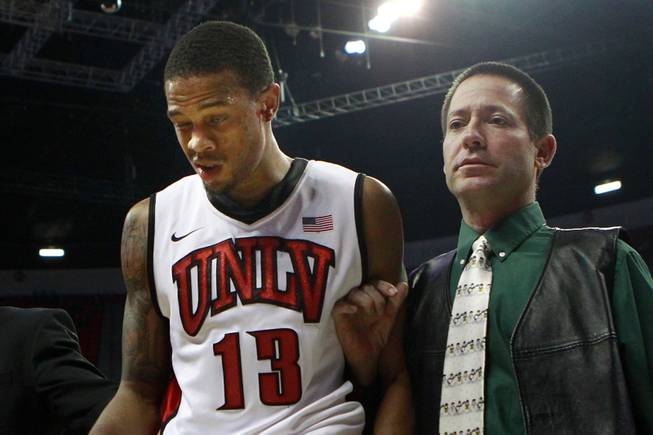 Trainer Dave Tomchek leads UNLV guard Bryce Dejean-Jones, bleeding from his ear, off the floor during their game against Canisius Saturday, Dec. 22, 2012 at the Thomas & Mack. The Runnin' Rebels won 89-74.