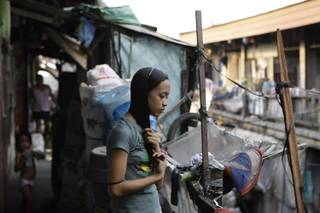 In this photo taken Dec. 4, 2012, Filipino slum dweller Jessa Balote holds her hair outside her cramped home at a place called Aroma in Tondo, Manila, Philippines. Balote, who used to tag along with her family as they collect garbage at a nearby dumpsite, is a scholar at Ballet Manila's dance program. As an apprentice, she makes around 7,000 pesos ($170) a month, sometimes double that, from stipend and performance fees.