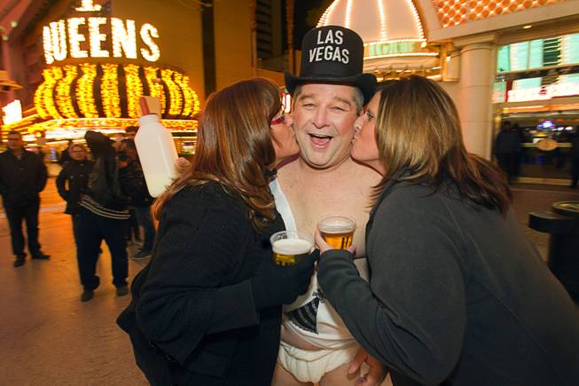 "Tank" Campbell of North Carolina gets kisses from Cheryl Strassman, left, and Becky Vanheubel of Appleton, Wis. during the New Years Eve party at the Fremont Street Experience Monday, Dec. 31, 2012. Campbell, a truck driver who is on a layover in Las Vegas, said it was his first time to work as a street performer.