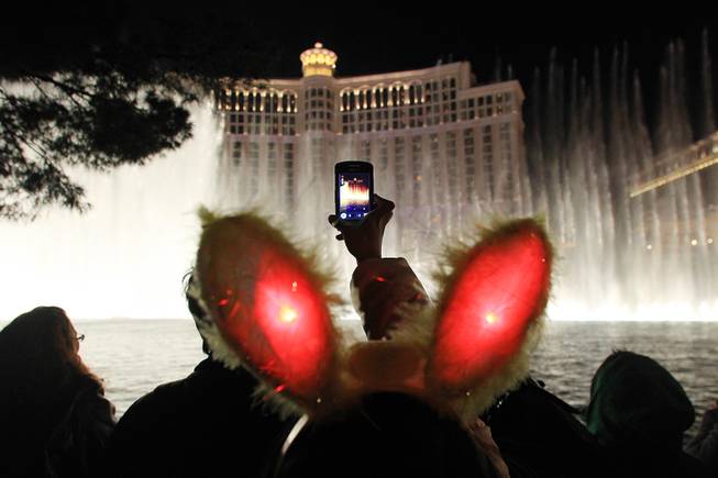 A reveler takes video of the Bellagio fountains during the New Year's Eve celebration on the Strip Monday, Dec. 31, 2012.