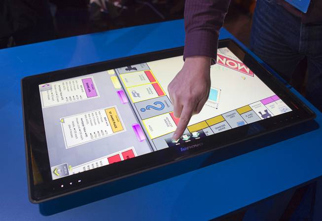 A man tries out a Monopoly game on a Lenovo's IdeaCentre Horizon Table PC during an Intel press conference at the 2013 International CES in the Mandalay Bay Convention Center Monday, January 7, 2013. Intel announced improvements to its processors including one with "all day" battery life. Intel also announced the availability of live and on-demand pay TV content to Intel devices.