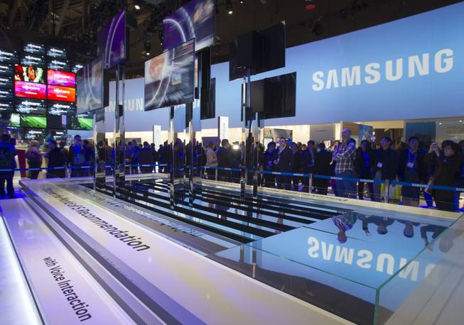 Show-goers watch a display of Samsung Smart TVs during the first day of the 2013 International CES in the Las Vegas Convention Center Tuesday, Jan. 8, 2013. The televisions have voice interaction and can make recommendations based on the consumer's viewing habits. 