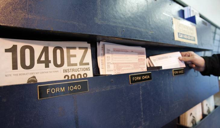 A man picks up federal tax form 1040 at a post office in Palo Alto, Calif., Wednesday, April 15, 2009. 