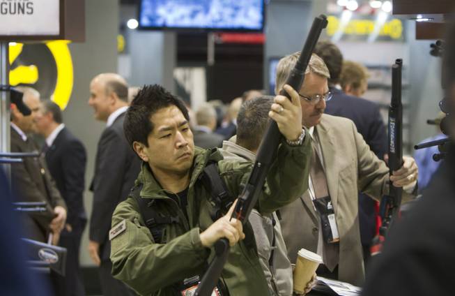 Paul Hwang of Auburn, Wash., looks over a Mossberg shotgun during the annual SHOT (Shooting, Hunting, Outdoor Trade) Show in the Sands Expo Center, Jan. 15, 2013. Gun dealers at the show are reporting booming sales resulting from worries about possible gun control legislation. 