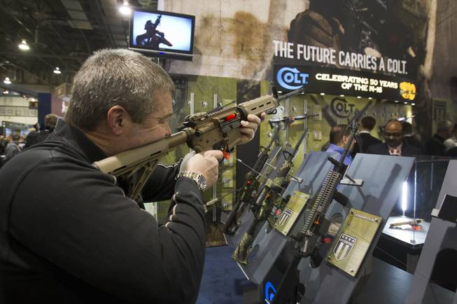 Mark Heitz, of Tactical Firearms in Kingston, N.H., looks over a civilian version of the Colt M4 carbine during the annual SHOT (Shooting, Hunting, Outdoor Trade) Show in the Sands Expo Center Tuesday, Jan. 15, 2013. Gun dealers at the show are reporting booming sales resulting from worries about possible gun control legislation. STEVE MARCUS
