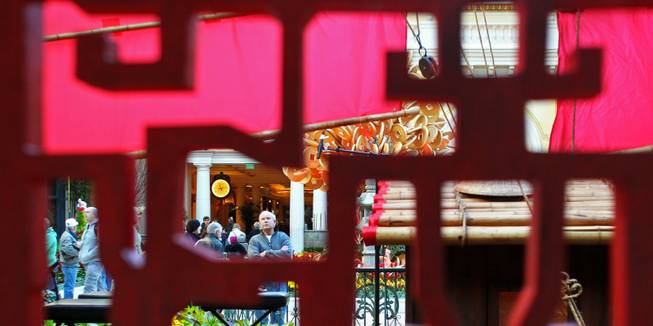 A man is seen through a Chinese wooden screen at the Bellagio Conservatory & Gardens Chinese New Year display Tuesday, Jan. 15, 2013.