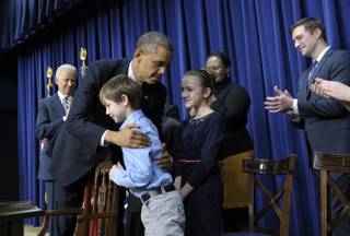 President Barack Obama, accompanied by Vice President Joe Biden, left, hugs eight-year-old letter writer Grant Fritz during a news conference on proposals to reduce gun violence, Wednesday, Jan. 16, 2013, in the South Court Auditorium at the White House in Washington. Obama and Biden were joined by law enforcement officials, lawmakers and children who wrote the president about gun violence following the shooting at an elementary school in Newtown, Conn., last month.