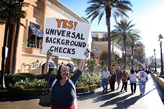 Sandra Minor of Las Vegas holds up a sign during a demonstration in favor of President Obama's new gun regulations outside of the Palazzo on the Strip in Las Vegas on Saturday, January 19, 2013.