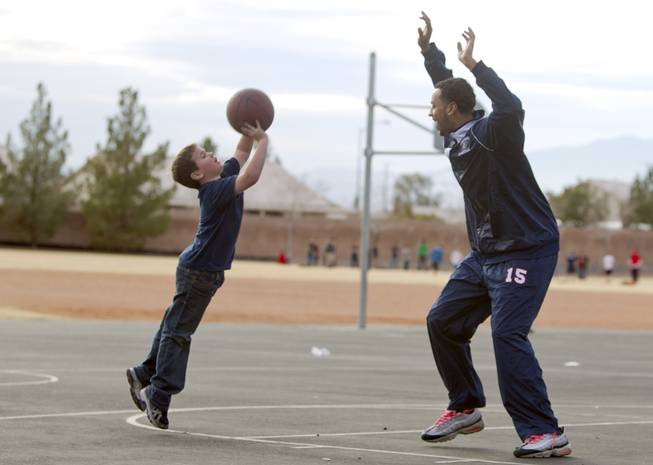 First grader Nolan Roos shoots over Coronado High School basketball player Jordan Willis during a one-on-one game on the playground at Glen Taylor Elementary School in Henderson on Wednesday, Jan. 23, 2013. Coronado basketball players and cheerleaders take time out of their season to mentor first- and second-graders at the school.