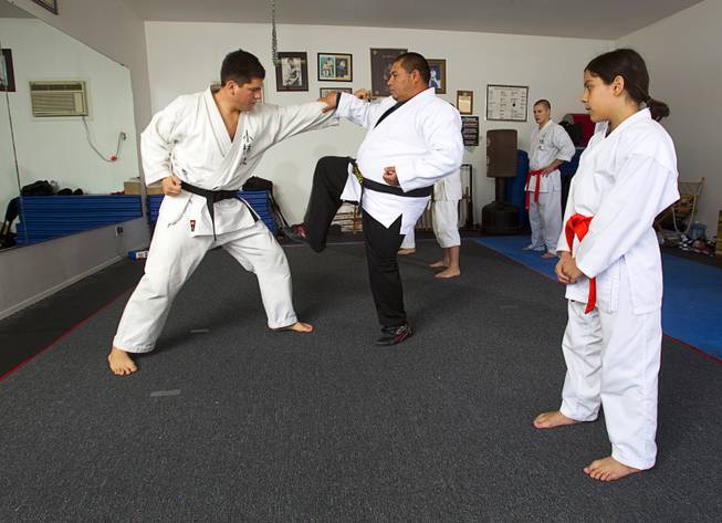 Shorin-ryu karate instructors Andy Dowdell, left, and Mauro Felix, fifth degree black belts, demonstrate a technique for students during a class at his home Sunday, Jan. 27, 2013.