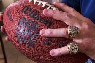 Mike Cofer, an assistant football coach at Coronado High School, holds a Super Bowl XXIV game ball at his home in Henderson, Wednesday, Jan. 30, 2013. Cofer was an NFL kicker and played with the San Francisco 49ers during Super Bowl wins in 1989 and 1990. The rings are from XXIV, top, and XXIII.
