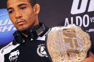 Jose Aldo carries his lightweight championship belt during the news conference for UFC 156 Thursday, Jan. 31, 2013.