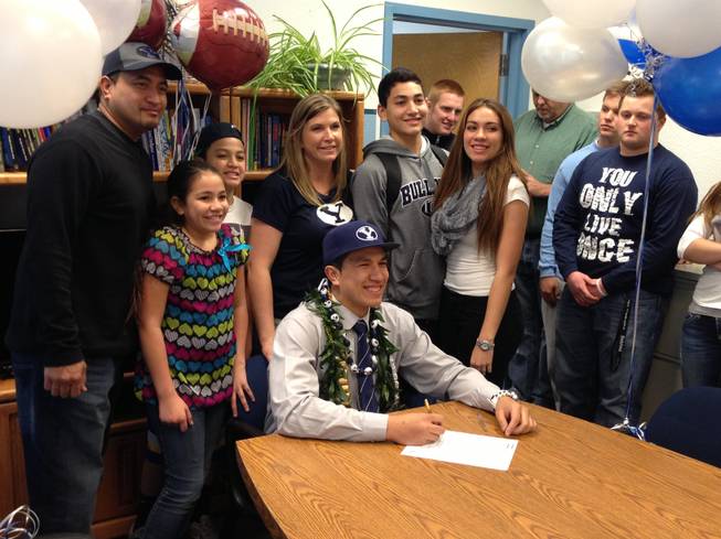 Centennial defensive end Trajan Pili signs his letter of intent to play for Brigham Young University with his family by his side on Wednesday February 6.