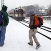 Two travelers walk to catch the last train into Boston from the Andover, Mass., train station as snow falls on Friday, Feb. 8, 2013.