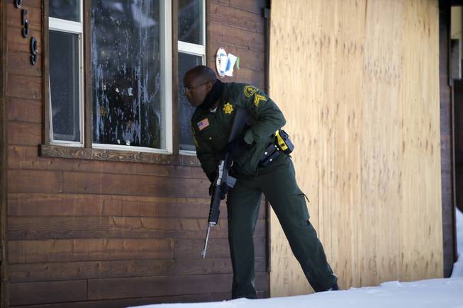 San Bernardino County Sheriff's officer Ken Owens searches a home for former Los Angeles police officer Christopher Dorner in Big Bear Lake, Calif., on Sunday, Feb. 10, 2013. The hunt for the former Los Angeles police officer suspected in three killings entered its fourth day in the snow-covered mountains on Sunday, a day after the police chief ordered a review of the disciplinary case that led to the fugitive's firing and new details emerged of the evidence he left behind.