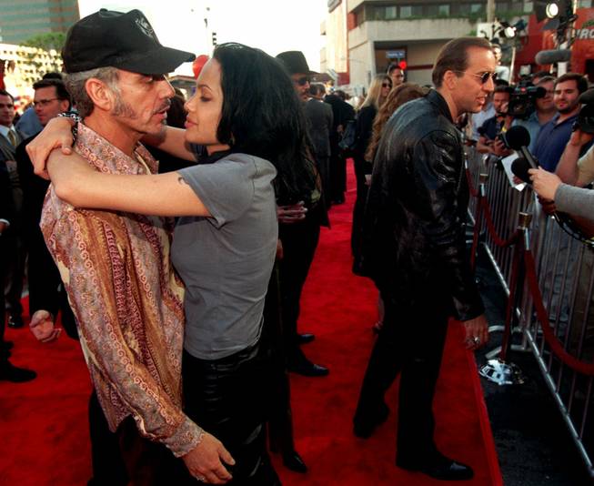 Actress Angelina Jolie, one of the stars of the new action film "Gone in 60 Seconds," nuzzles with her husband, actor Billy Bob Thornton, as her co-star Nicolas Cage, at right, speaks to reporters at the premiere of the film, Monday, June 5, 2000, in the Westwood section of Los Angeles. 