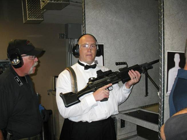This July 28, 2012, photo provided by Bob MacDuff shows MacDuff holding an automatic weapon at the Gun store in Las Vegas after his "shotgun wedding." One Las Vegas shooting range is selling “take a shot at love” packages that include 50 submachine gun rounds. Another is offering wedding packages in which the bride and groom can pose with Uzis and ammunition belts. And a third invites lovebirds to renew their vows and shoot a paper cutout zombie in the face.