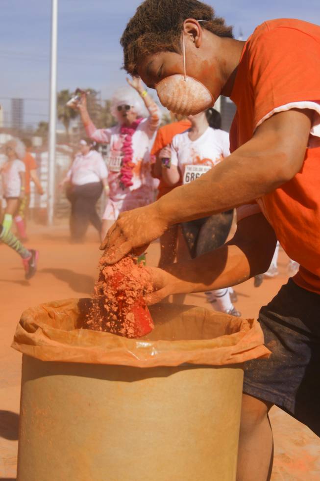 A volunteer fills up a bottle with orange powder at 5K Color Run, Saturday, Feb. 16, 2013. 