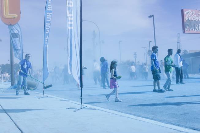 Kelly Lutzker sweeps up the blue powder as other volunteers are seen waiting in a blue haze for participants to run through the blue stage of the 5K Color Run, Saturday, Feb. 16, 2013. 