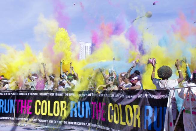 Packets of colored powder fly through the air at the color extravaganza finish line at the 5K Color Run, Saturday, Feb. 16, 2013, in downtown Las Vegas.