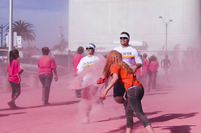 A volunteer hits a couple with pink powder as they pass the pink stage of the 5K Color Run, Saturday, Feb. 16, 2013.
