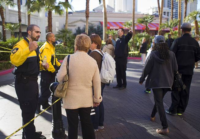 Security officers at the Flamingo give instructions to tourists near the site of a shooting and multi-car accident that left three people dead and at least three injured on the Las Vegas Strip early Thursday morning, Feb. 21, 2013. Most tourists had already heard about the shooting by the afternoon but needed directions on how to navigate around the crime scene.