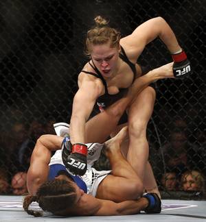 Ronda Rousey, top, punches Liz Carmouche during their UFC 157 women's bantamweight championship mixed martial arts match in Anaheim, Calif., Saturday, Feb. 23, 2013. Rousey won the first womens bout in UFC history, forcing Carmouche to tap out in the first round. (AP Photo/Jae C. Hong)