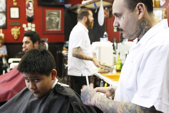 Michelangelo Estrada looks up while getting his hair cut by Martin Corona at Hi Rollers Barber Shop Saturday, Feb. 23, 2013.