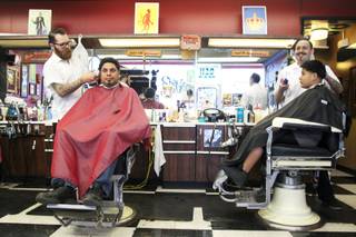Brad Hogarth works on Turbo Proctor, left, while Michelangelo Estrada gets his hair cut by Martin Corona at Hi Rollers Barber Shop Saturday, Feb. 23, 2013.