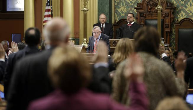 Members of the Michigan House are sworn in by Chief Justice of the Michigan Supreme Court Justice Robert Young, back right, in Lansing, Mich., Wednesday, Jan. 9, 2013. Twenty-eight new lawmakers are joining the GOP-controlled Michigan Legislature on the first day of the next two-year session. The new House members were sworn in shortly after noon Wednesday along with those re-elected to the 110-member chamber.