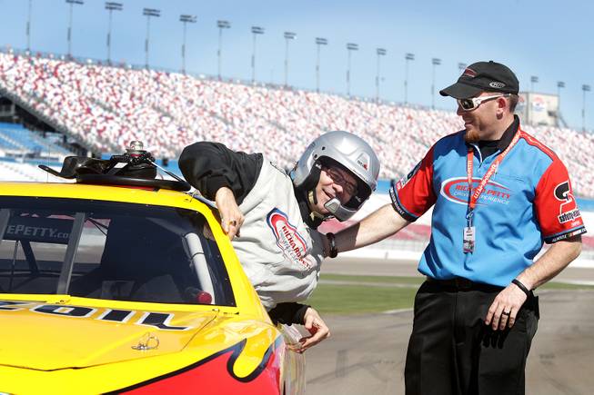John Katsilometes gets out of his race car with some help from operations manager Corrie Matthews of the Richard Petty Driving Experience at Las Vegas Motor Speedway on Friday, March 1, 2013.