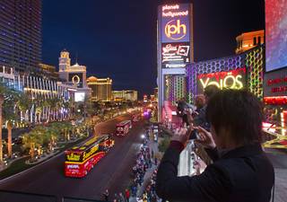 A Japanese tourist, right, takes photos during a parade of NASCAR haulers on the Las Vegas Strip Wednesday, March 6, 2013.  The NASCAR hauler parade traveled north on the Las Vegas Strip to Sahara Avenue, then on I-15 to the Las Vegas Motor Speedway.