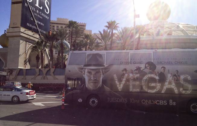 The partial Sahara sign sits behind a city bus advertising the tv show "Vegas" during the dismantling of the Sahara Casino sign, Tuesday, Mar. 12, 2013.