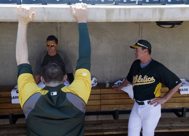 Oakland Athletics manager Bob Melvin, right. talsk to Josh Donaldson, left facing camera, and Jarrod Parker before an exhibition spring training baseball game against the Seattle Mariners on Monday, March 18, 2013 in Phoenix.