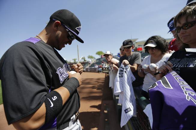 Colorado Rockies left fielder Carlos Gonzalez signs autographs before playing the Kansas City Royals in an exhibition spring training baseball game Tuesday, March 19, 2013, in Surprise, Ariz.