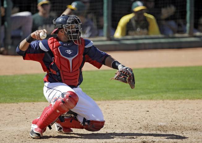 Cleveland Indians catcher Carlos Santana warms up his pitcher in an exhibition spring training baseball game against the Oakland Athletics Tuesday, March 26, 2013, in Goodyear, Ariz.